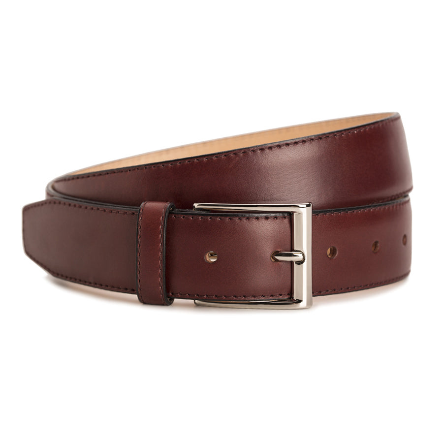 Meermin burgundy calf belt coiled, angled view highlighting nickel-plated buckle and stitched edge detail