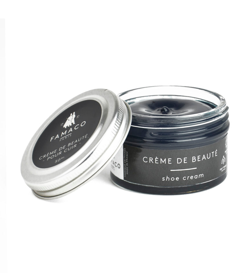 Famaco Crème de Beauté shoe cream jar open, showing black wax texture, lid resting beside it on white background