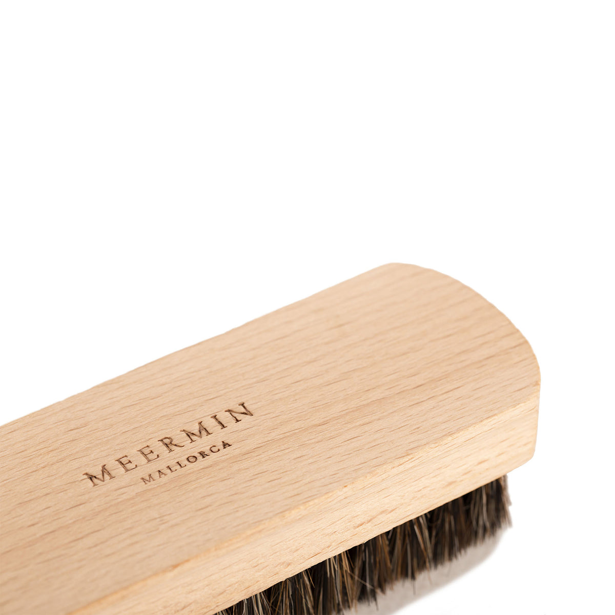 Close-up of beechwood shoe brush head with engraved logo, showing genuine horsehair bristles along the edge