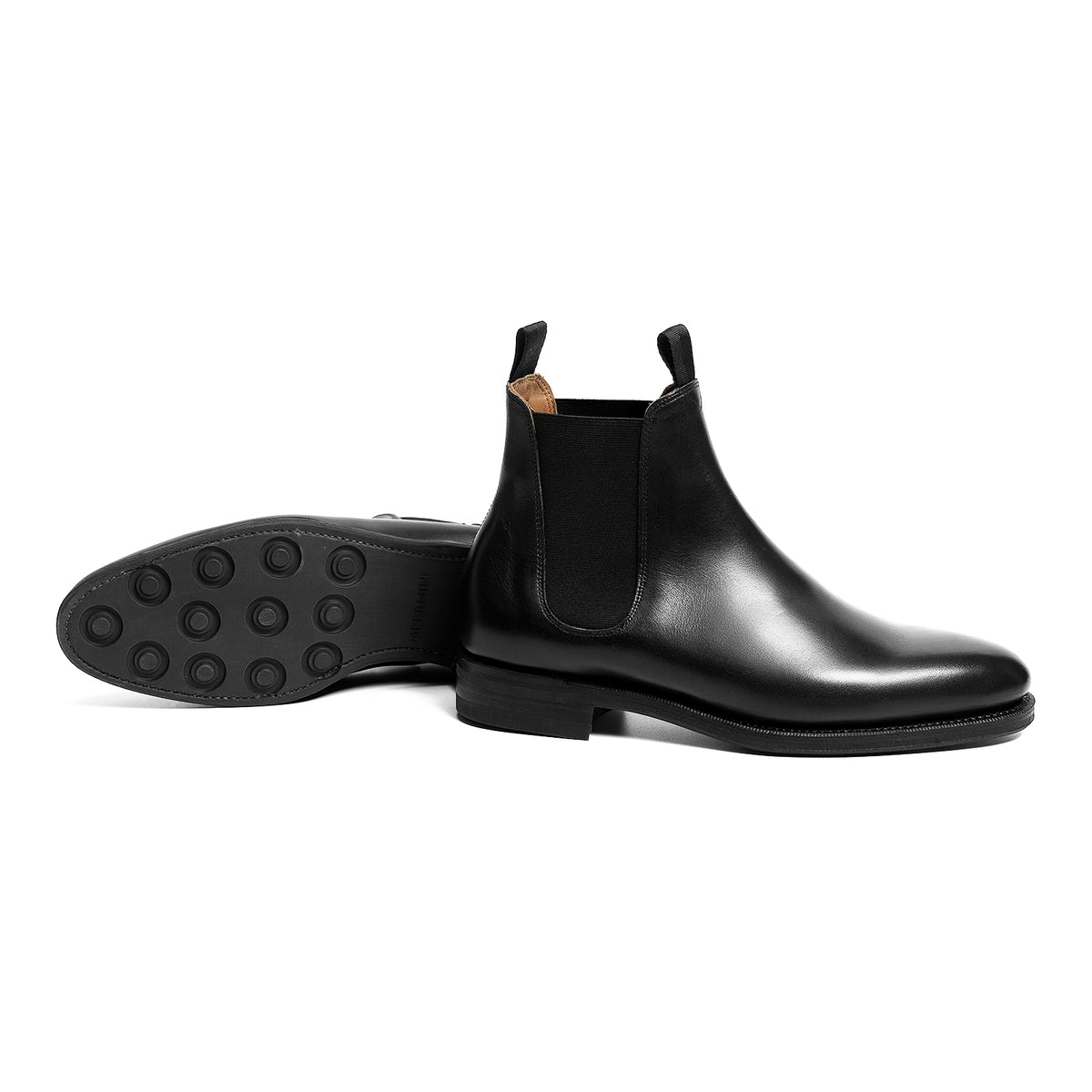 Meermin black boxcalf wholecut Chelsea boots, paired side profile with sole tread visible on the fallen boot behind