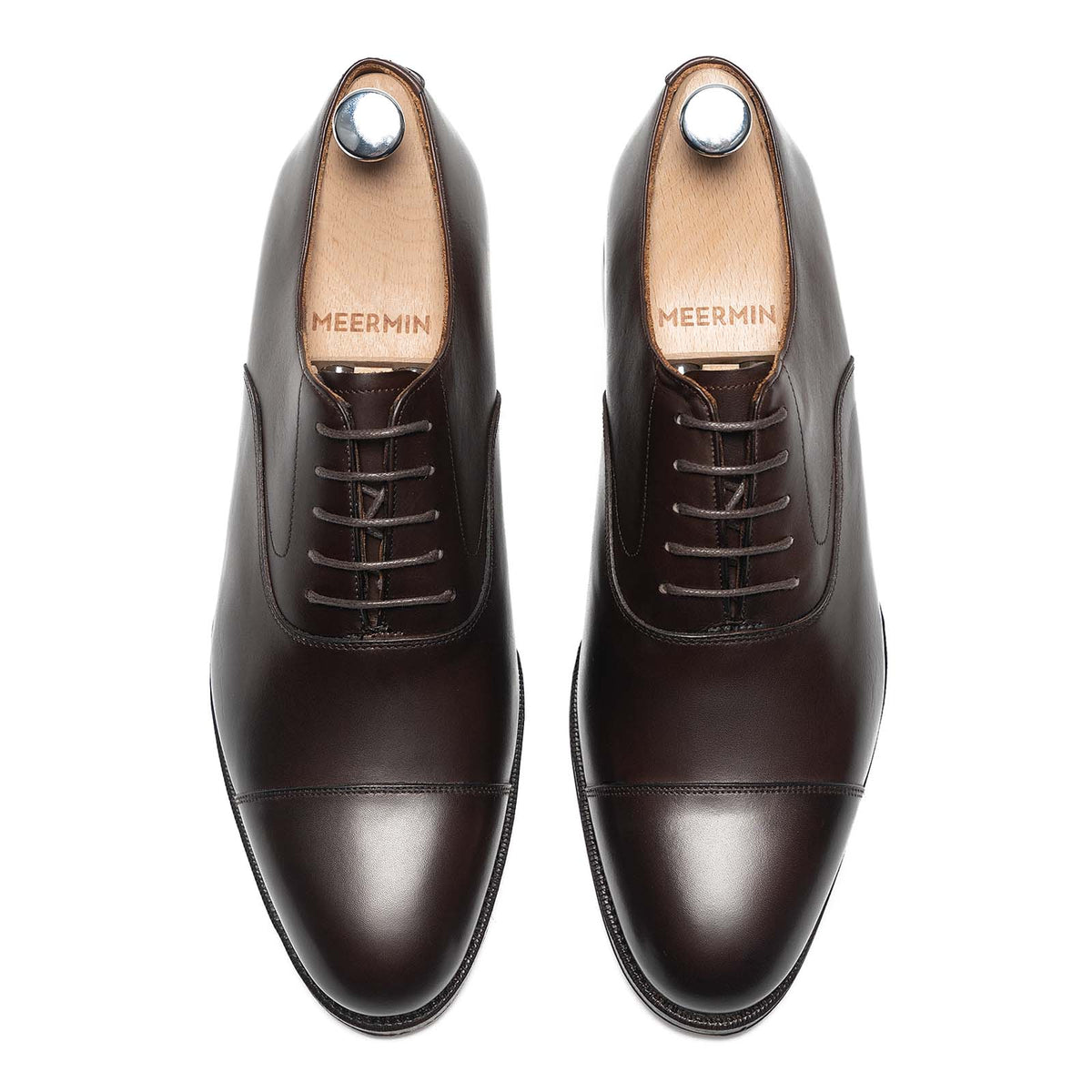 Meermin dark brown calfskin cap-toe Oxfords, top-down view of both shoes with wooden shoe trees inserted