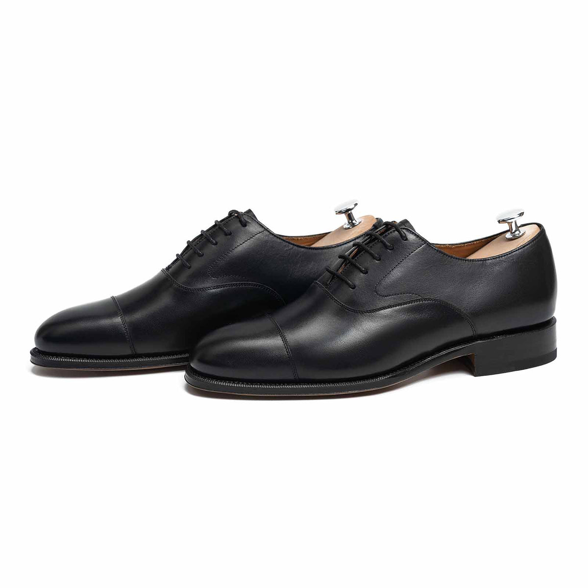 Meermin black boxcalf cap-toe Oxfords, pair shown at angle with shoe trees inserted, closed channel leather soles visible