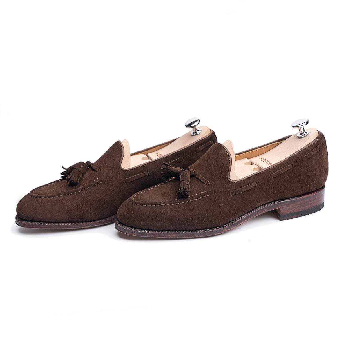 Meermin brown suede tassel loafers, three-quarter front view on shoe trees, showing hand-sewn apron and tassel detail