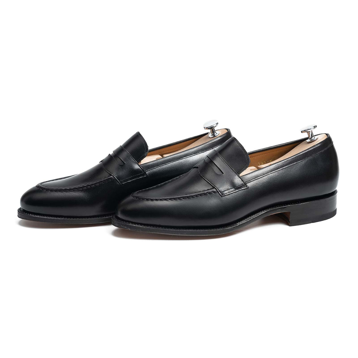 Meermin black calf penny loafers, three-quarter side view on shoe trees, showing closed channel leather sole and stacked heel