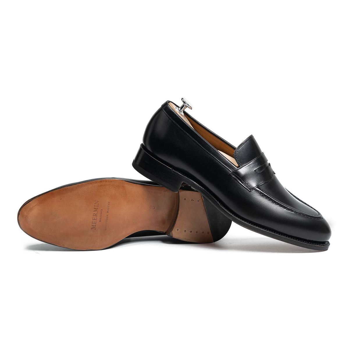 Meermin black calf penny loafers, paired shot showing side profile and sole, one shoe resting on shoe tree