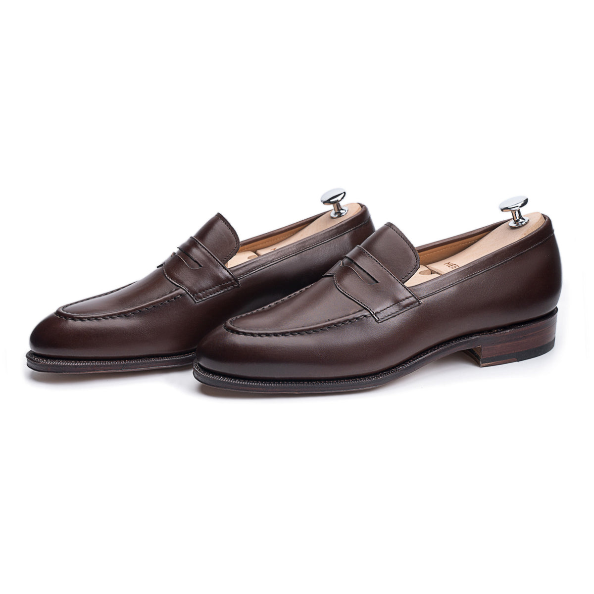 Meermin espresso antique calf penny loafers, three-quarter side view on shoe trees, showing apron stitching and stacked leather heel