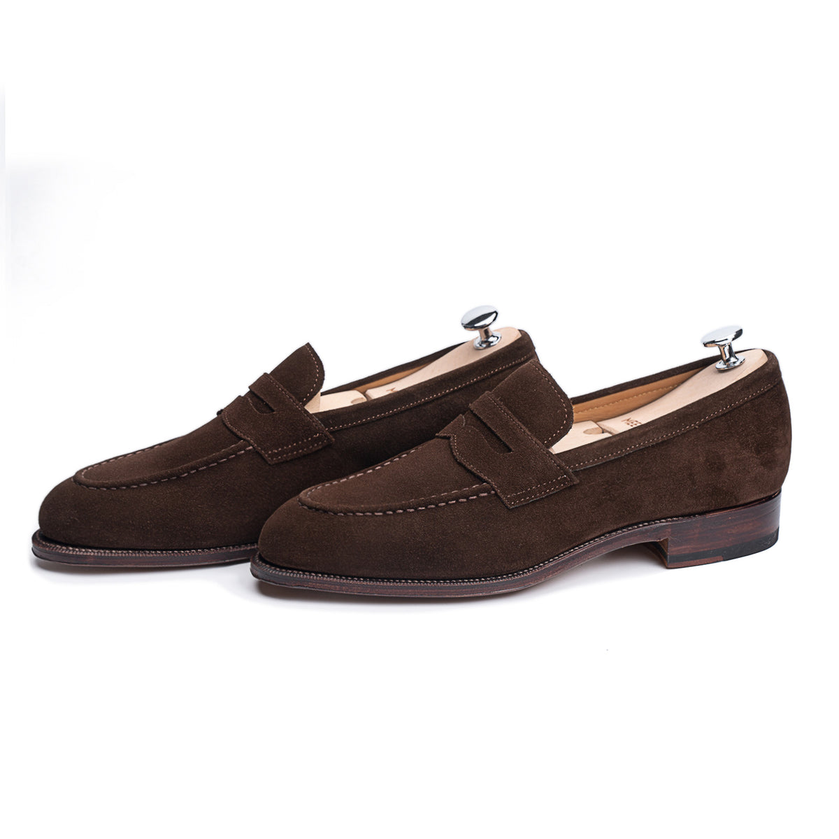 Meermin brown suede penny loafers, angled pair view with shoe trees inserted, showing apron stitching and stacked leather heels