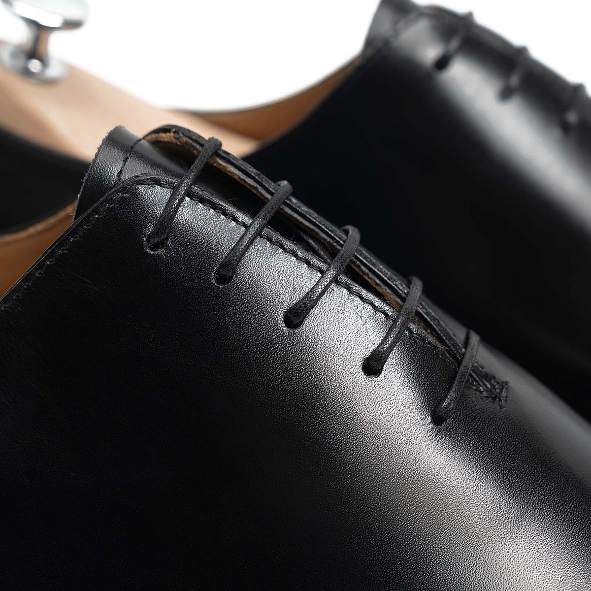 Meermin black boxcalf wholecut Oxford, close-up on lacing eyelets and stitching, shown on a wooden shoe tree
