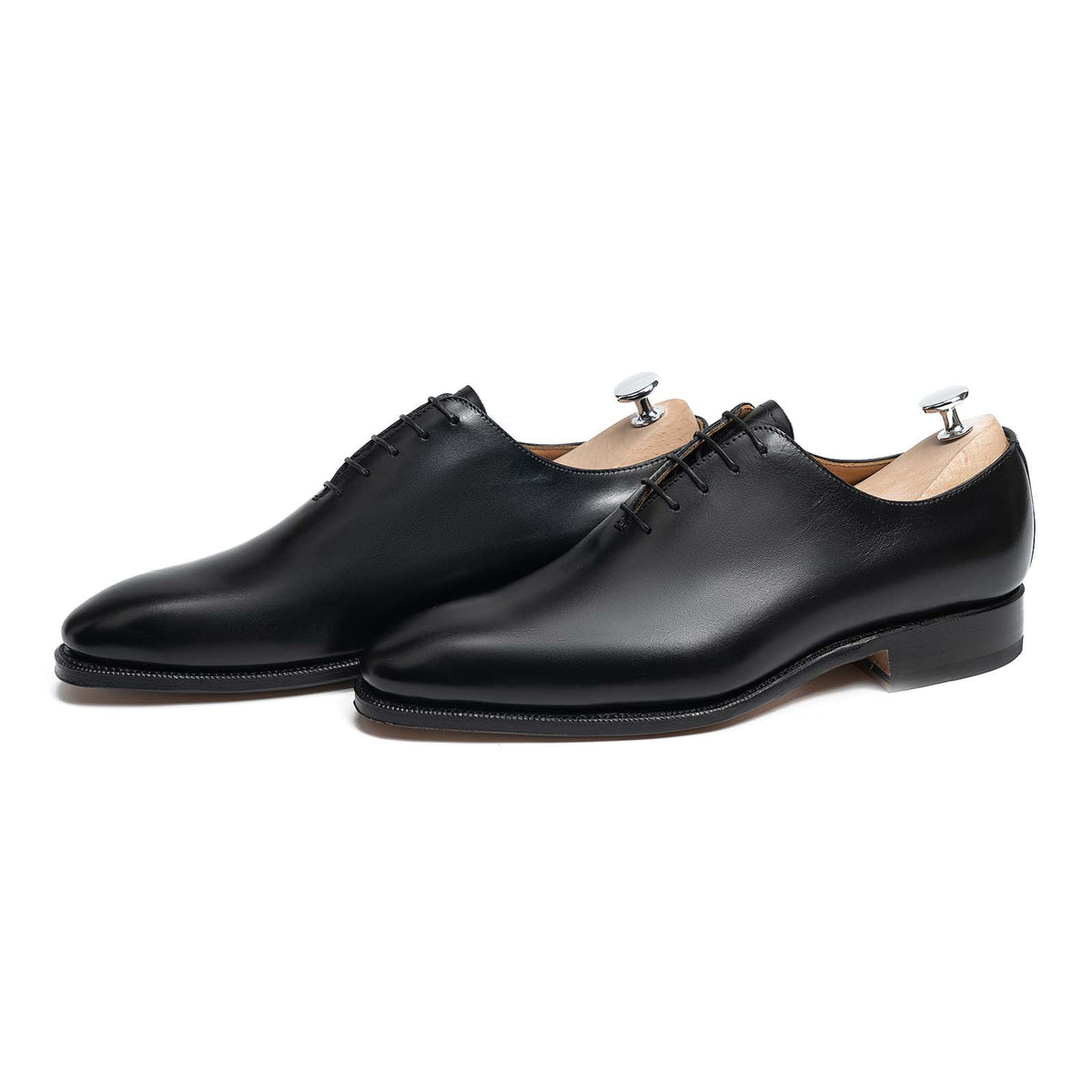 Meermin black boxcalf wholecut Oxford pair, angled front view with shoe trees inserted, showing closed channel sole edge