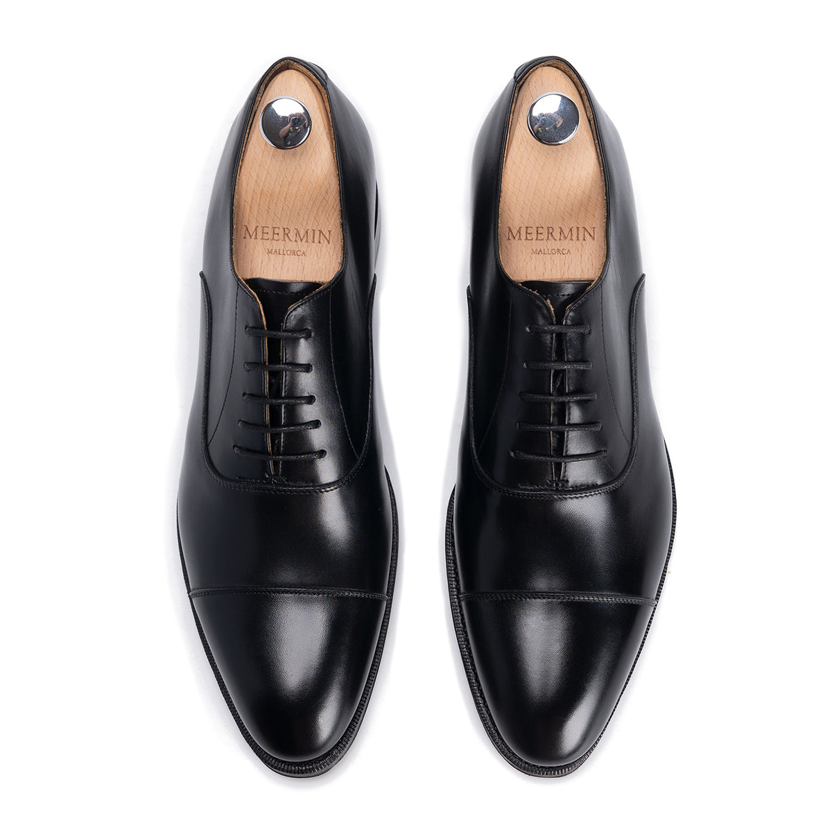 Meermin black calfskin cap-toe Oxfords, top-down view of both shoes with shoe trees inserted, showing lace detail and toe caps