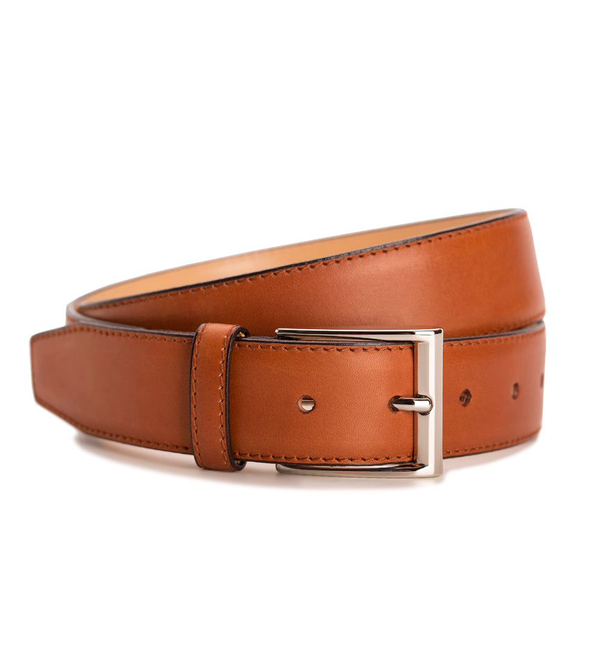 Meermin copper antique calfskin belt, coiled to show buckle and strap loop, nickel-plated solid brass buckle in focus
