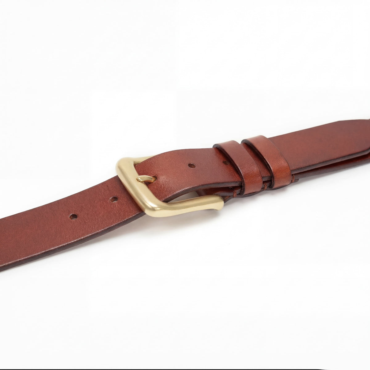Close-up of Meermin tobacco bridle leather belt's solid brass buckle and keeper loops, showing natural grain and stitching detail