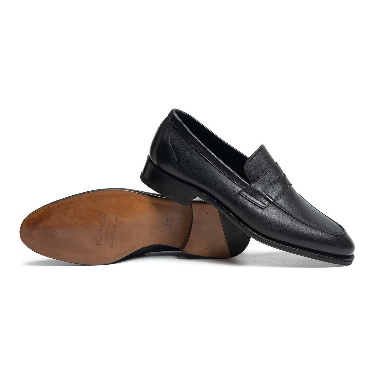 Meermin black softcalf penny loafers, side profile with one shoe overturned to show closed channel leather sole and heel