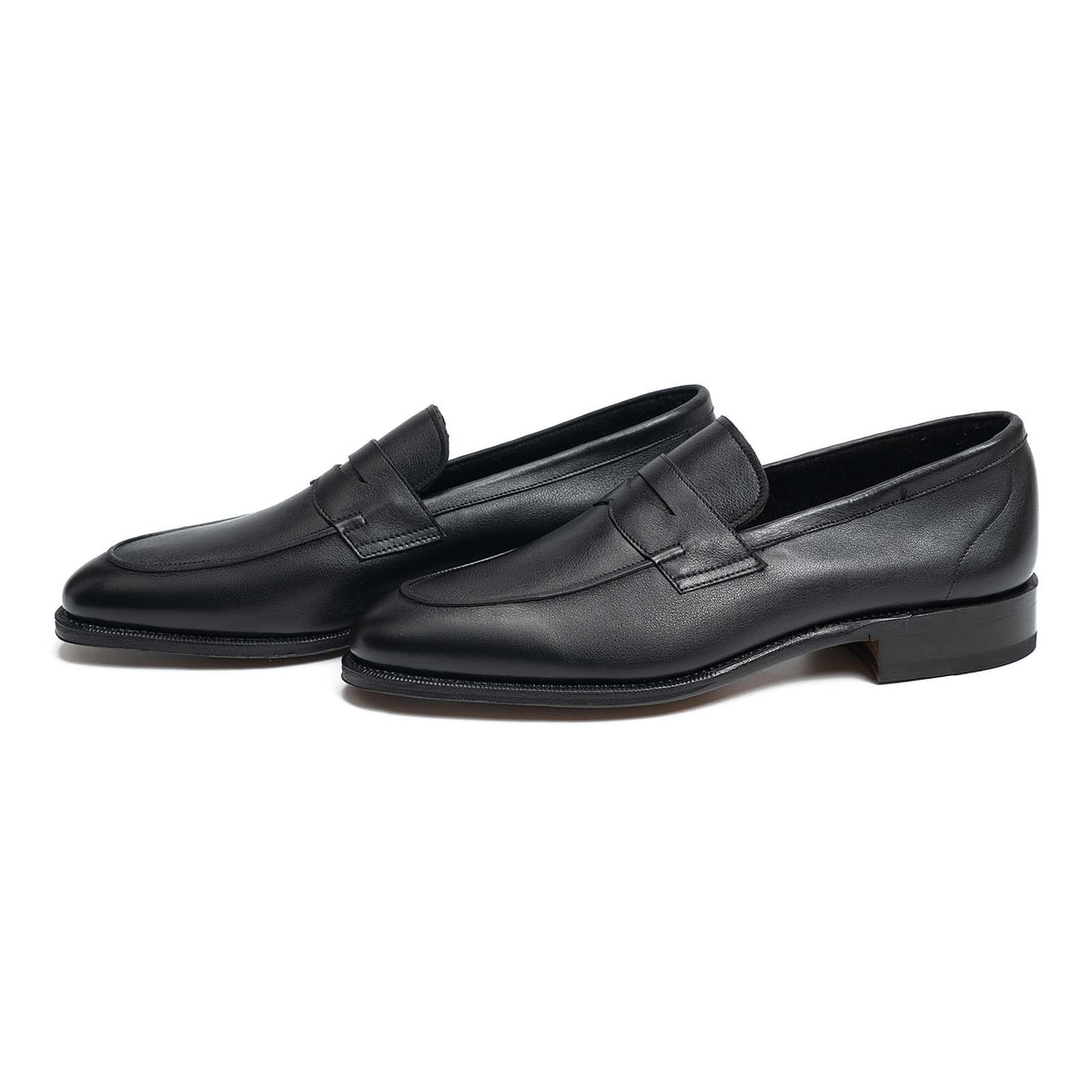 Meermin black softcalf unlined penny loafers, pair shown at an angle, showcasing closed channel leather sole and welt detail