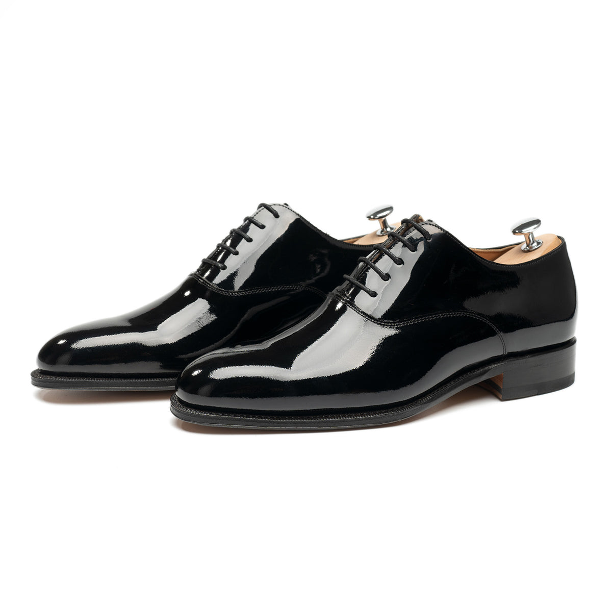 Meermin black patent Oxford pair, three-quarter front view with shoe trees inserted, showing high-shine leather and closed channel sole