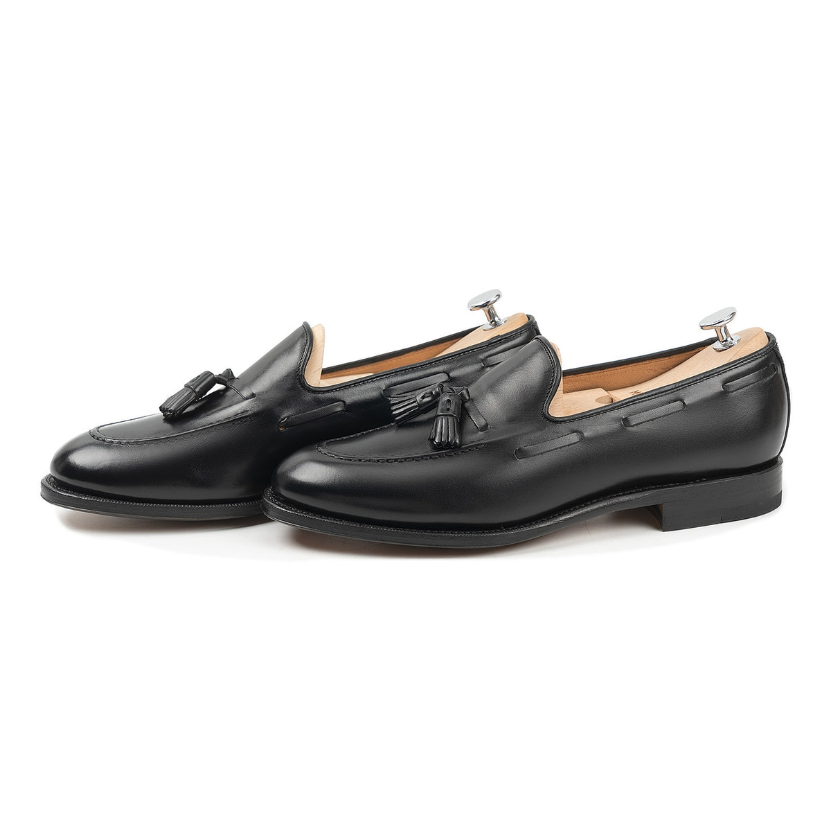 Meermin black calf tassel loafers, side-by-side three-quarter view on shoe trees, showing hand-sewn apron and tassel detail