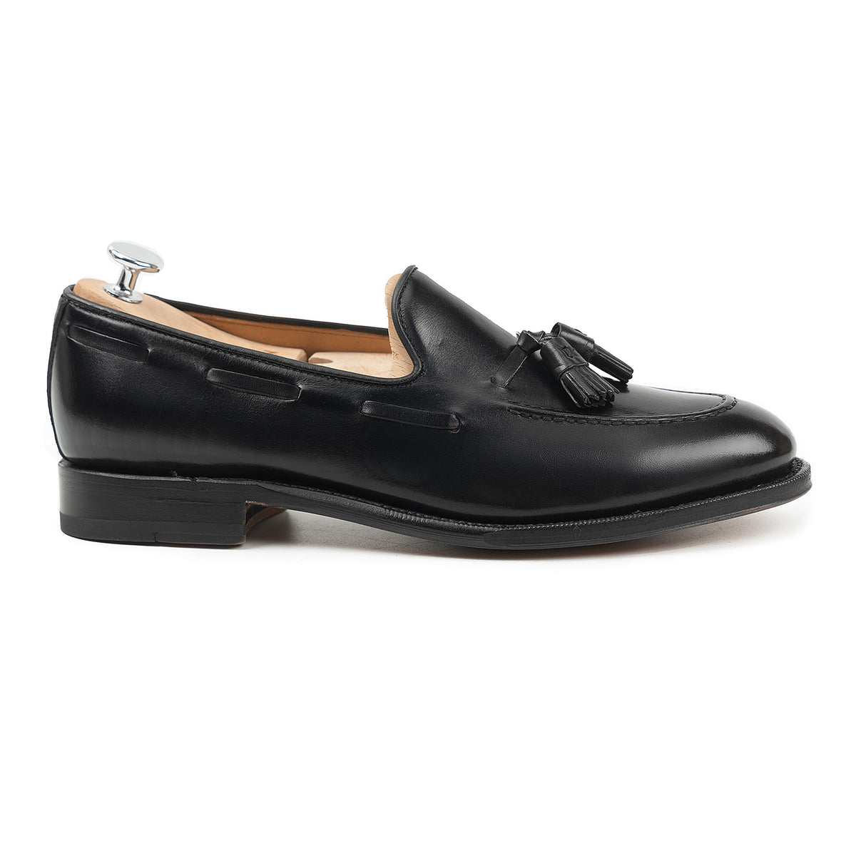 Meermin black calf tassel loafer, side profile on a shoe tree, showing the flex Goodyear welted sole and hand-closed tassels