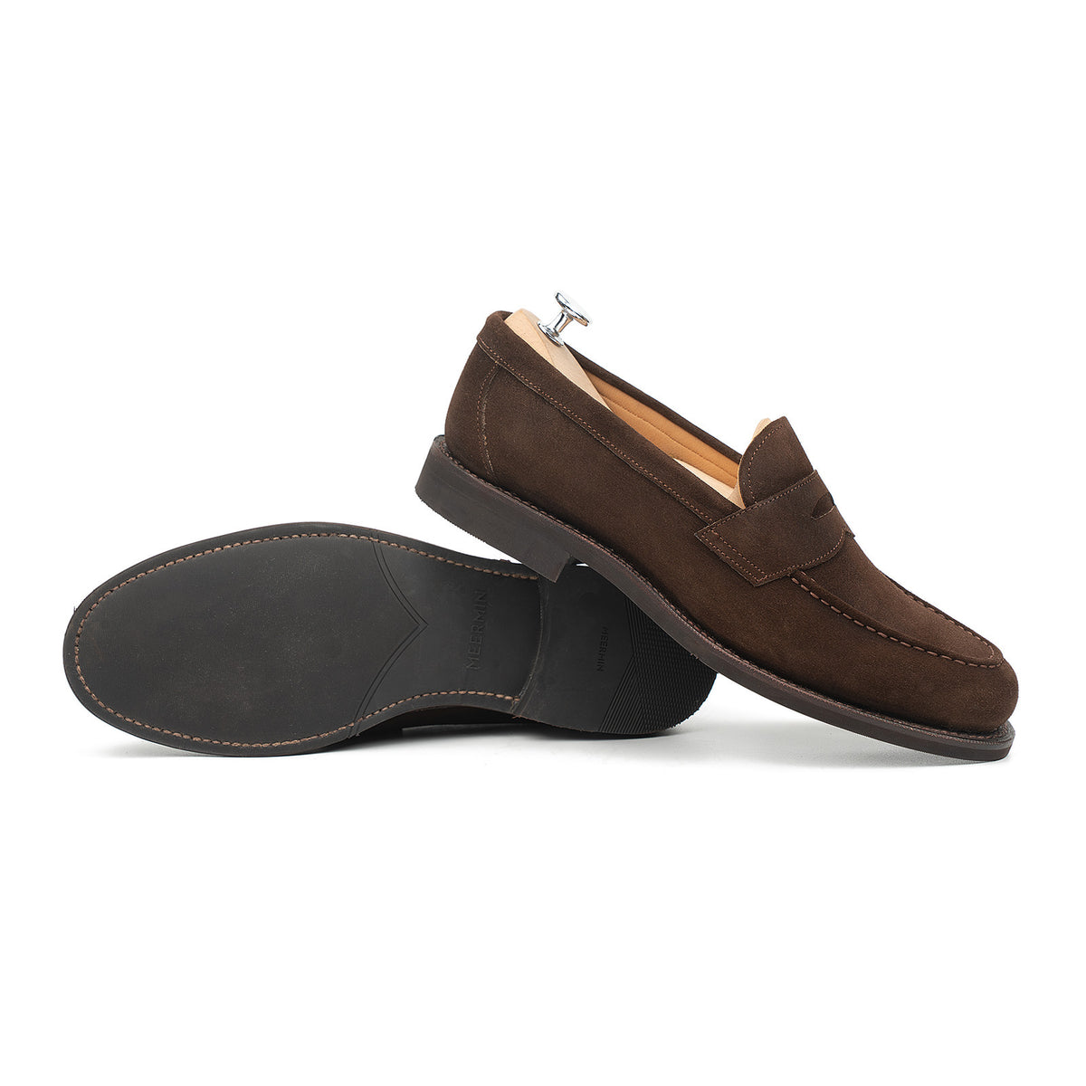 Meermin brown suede penny loafers shown side-on, one resting on shoe tree, the other upside-down revealing the rubber sole