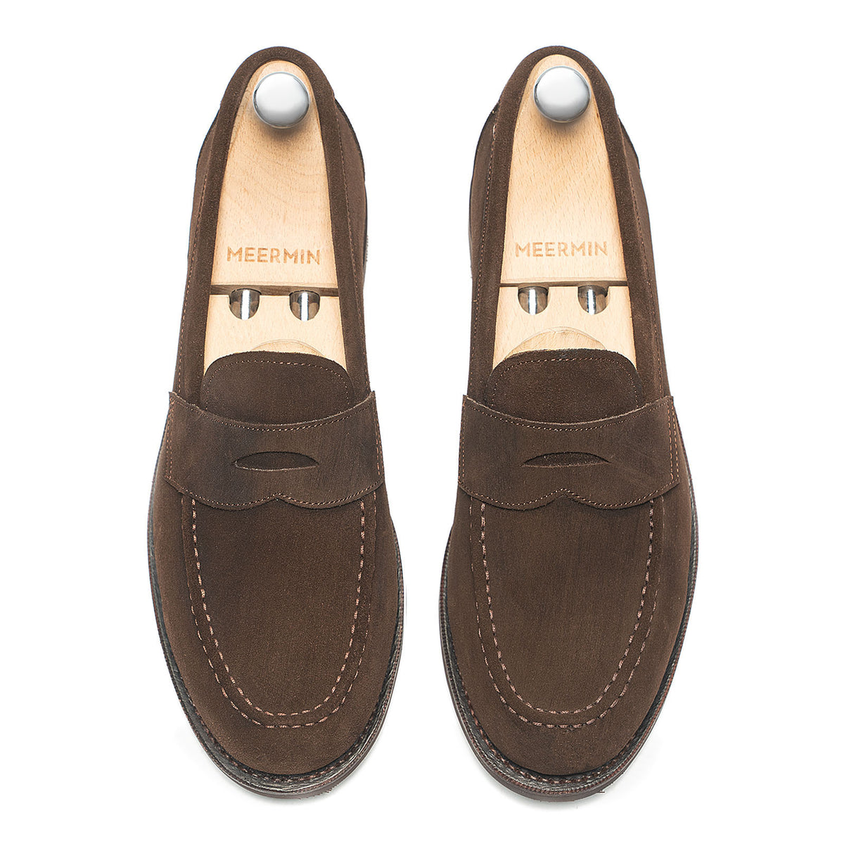 Top-down view of Meermin brown suede penny loafers on shoe trees, showing apron stitching and moc-toe seam detail