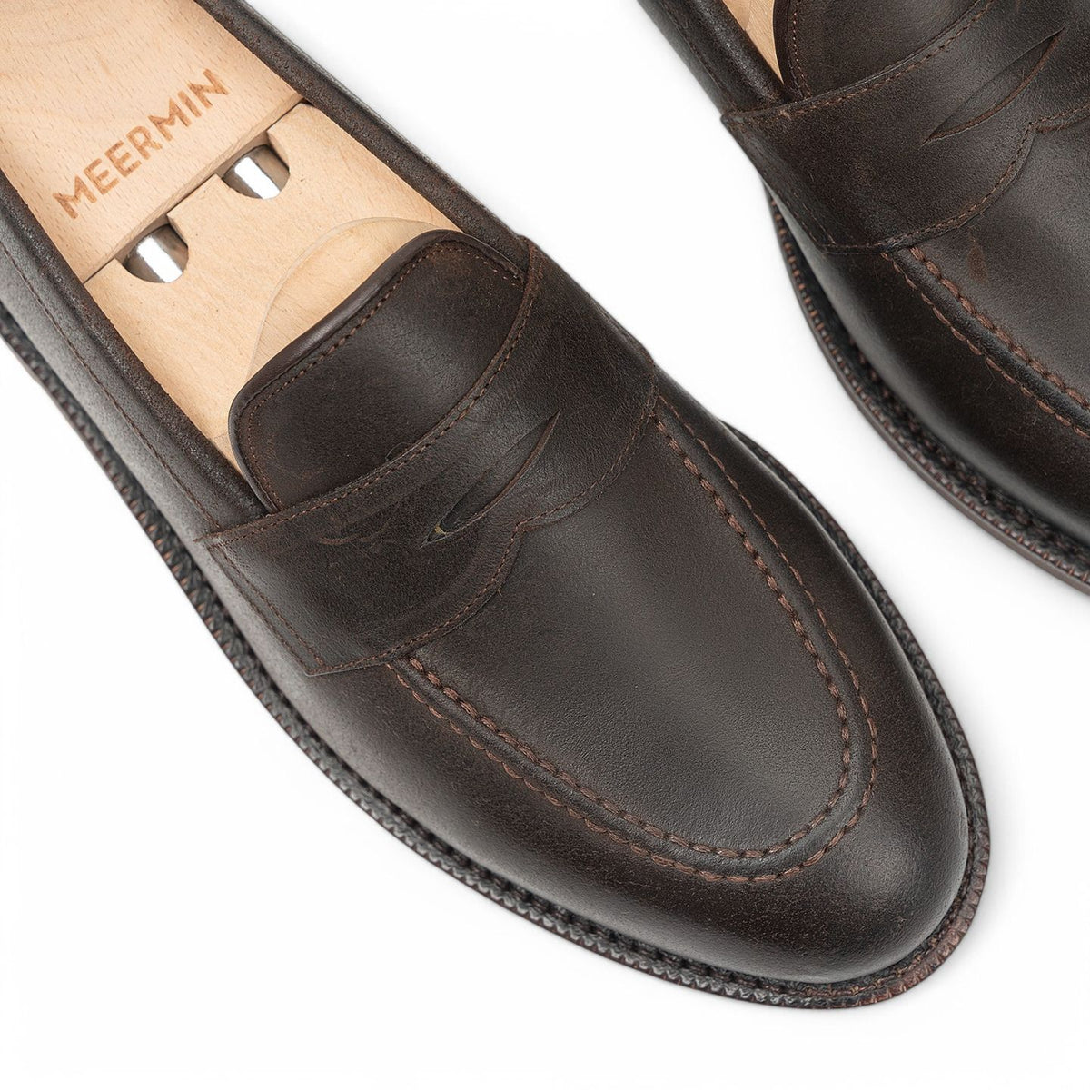 Meermin rust waxy Commander suede penny loafers, close-up top view on shoe trees showing strap and toe stitching detail