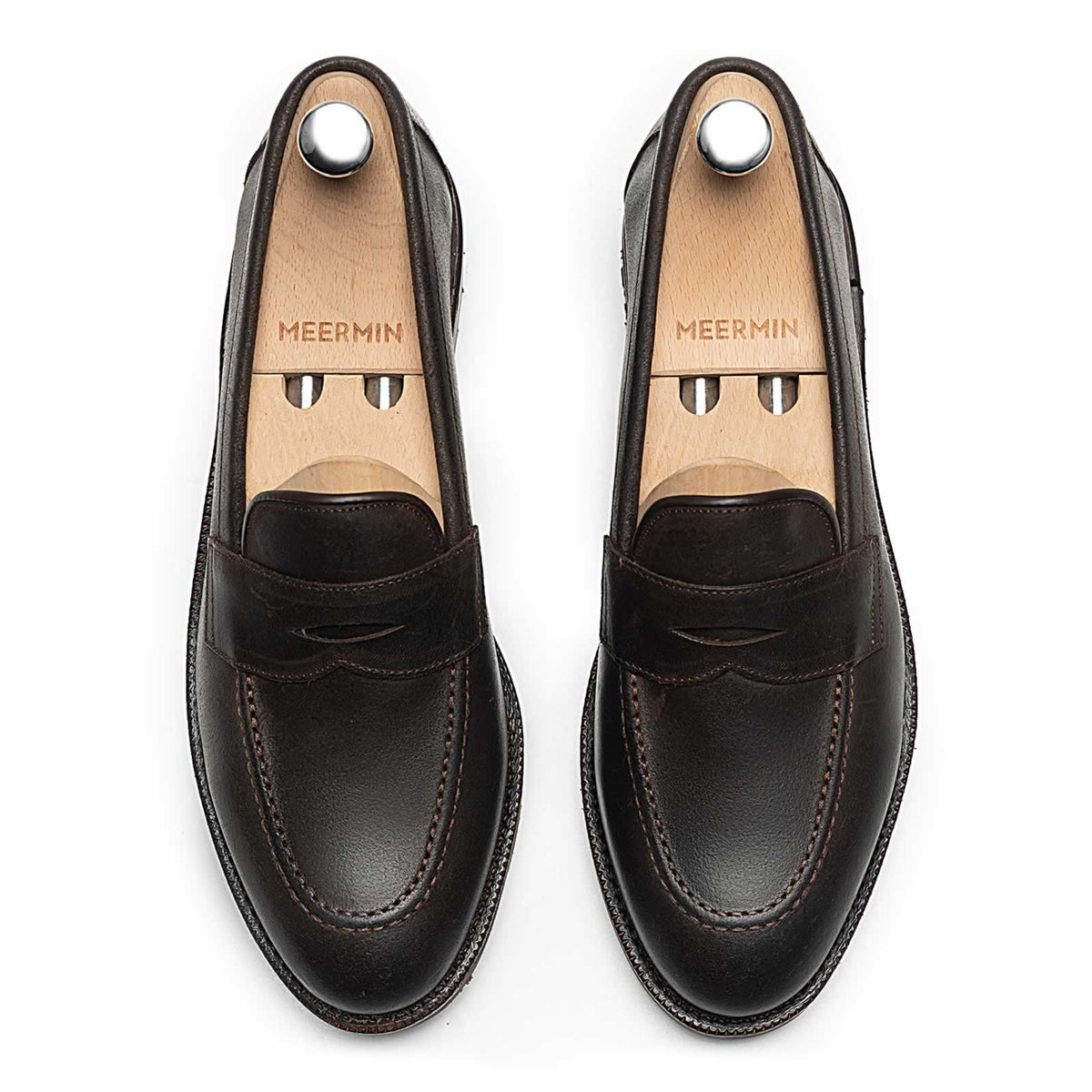 Meermin rust waxy Commander suede penny loafers, top-down view on shoe trees, showing moc-toe stitching and saddle detail