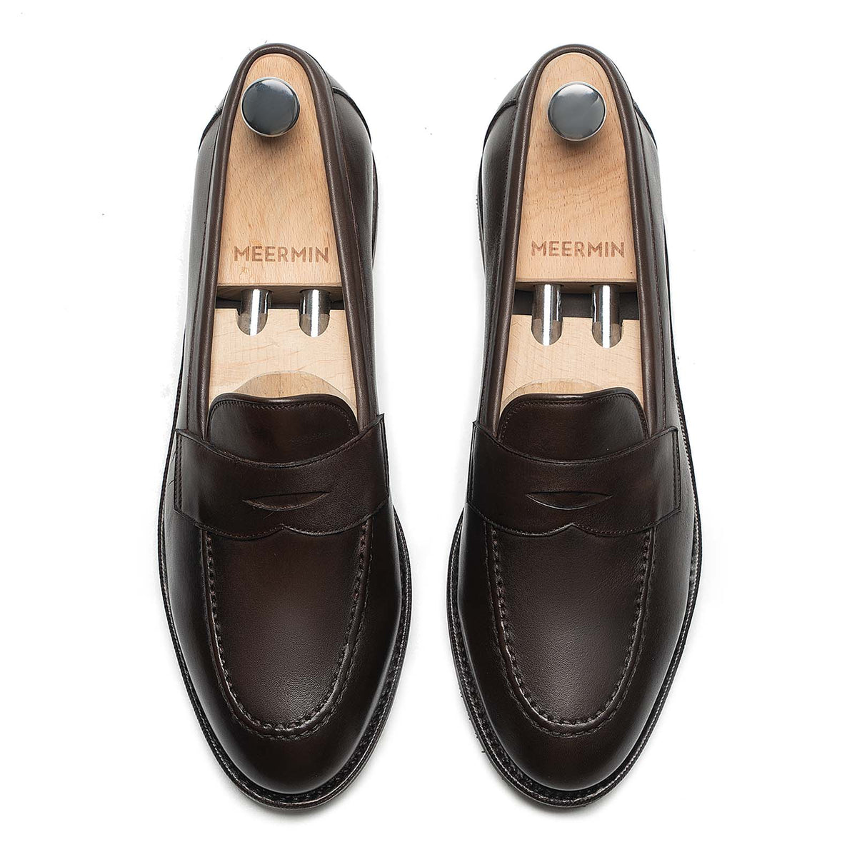 Meermin brown silkcalf penny loafers, top-down view of both shoes on wooden shoe trees showing apron stitching detail