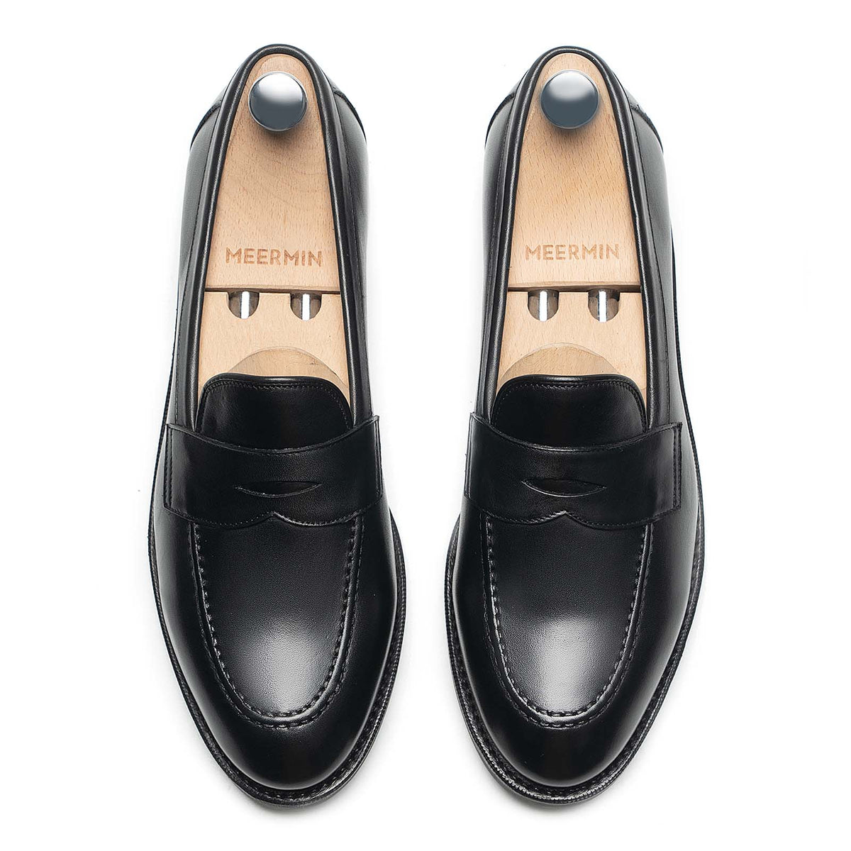 Meermin black silkcalf penny loafers, top-down view on shoe trees, showing handsewn apron and beveled waist