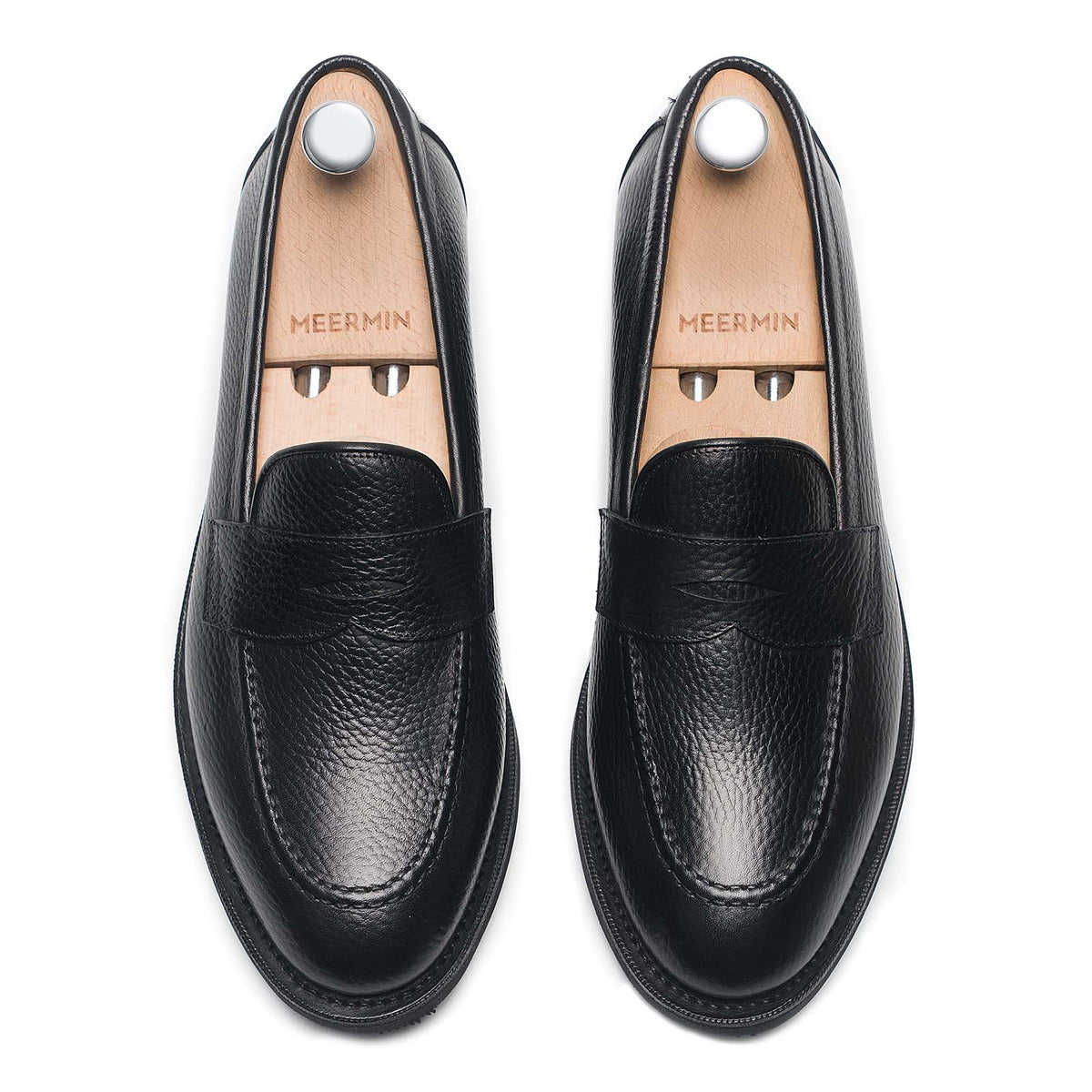 Meermin black Inca grain penny loafers, top-down view on shoe trees, showing handsewn aprons and moc-toe stitching