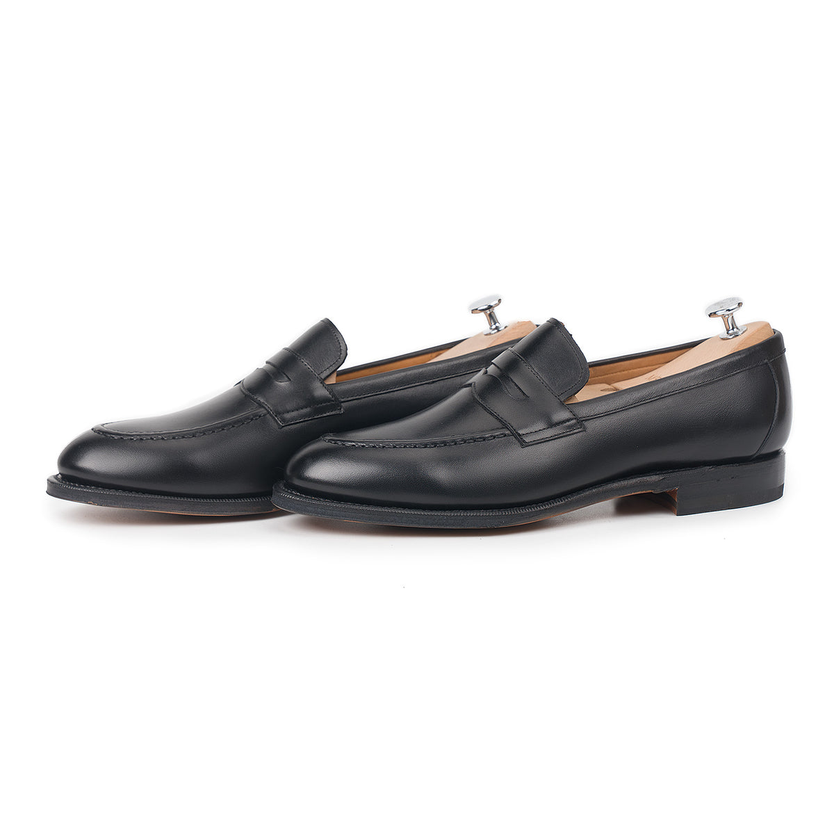 Meermin black boxcalf penny loafers, side-by-side three-quarter view with shoe trees inserted, showing saddle strap and closed-channel sole