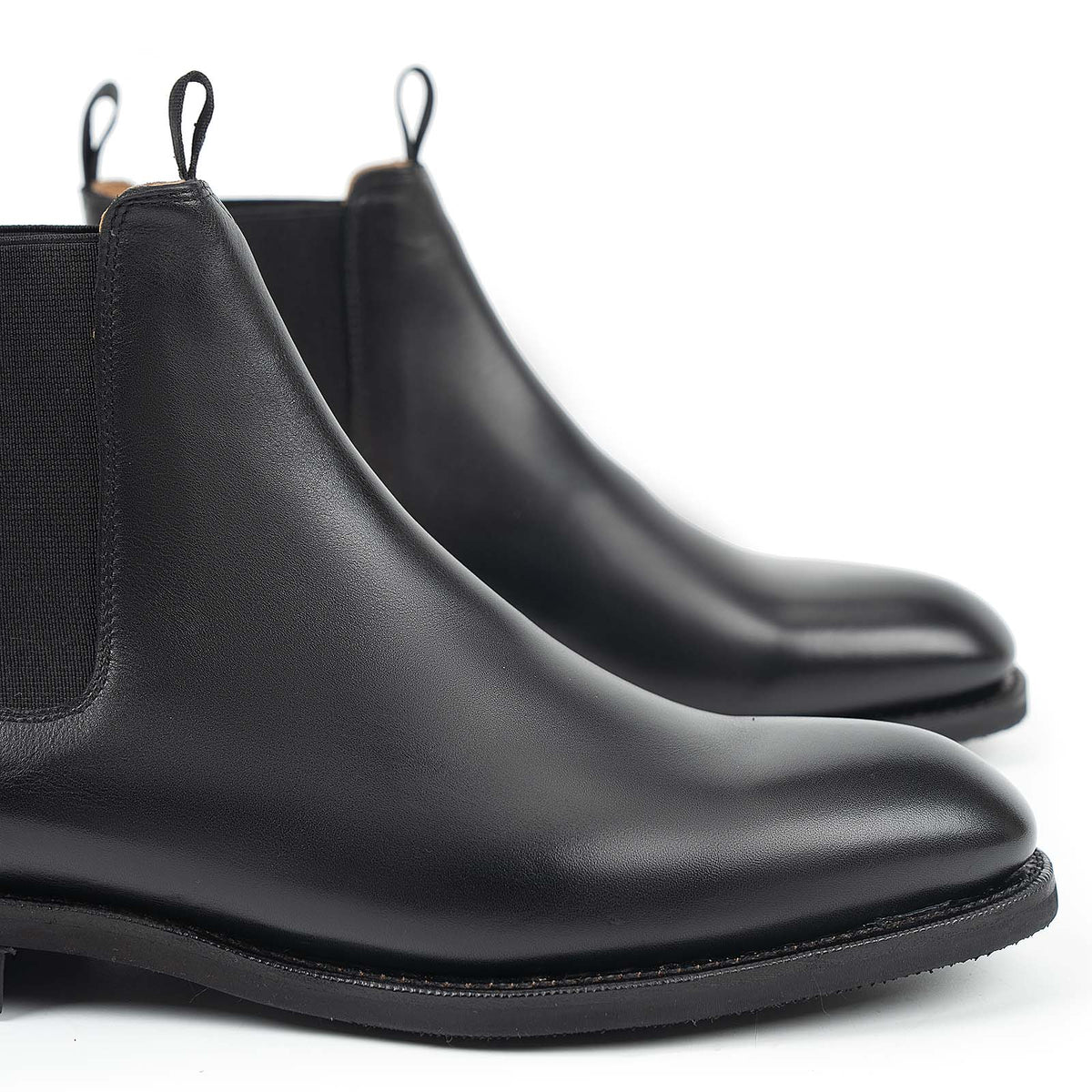 Meermin black silkcalf Chelsea boots, close-up side view showing elastic panels, pull tabs, and diamond latex rubber soles