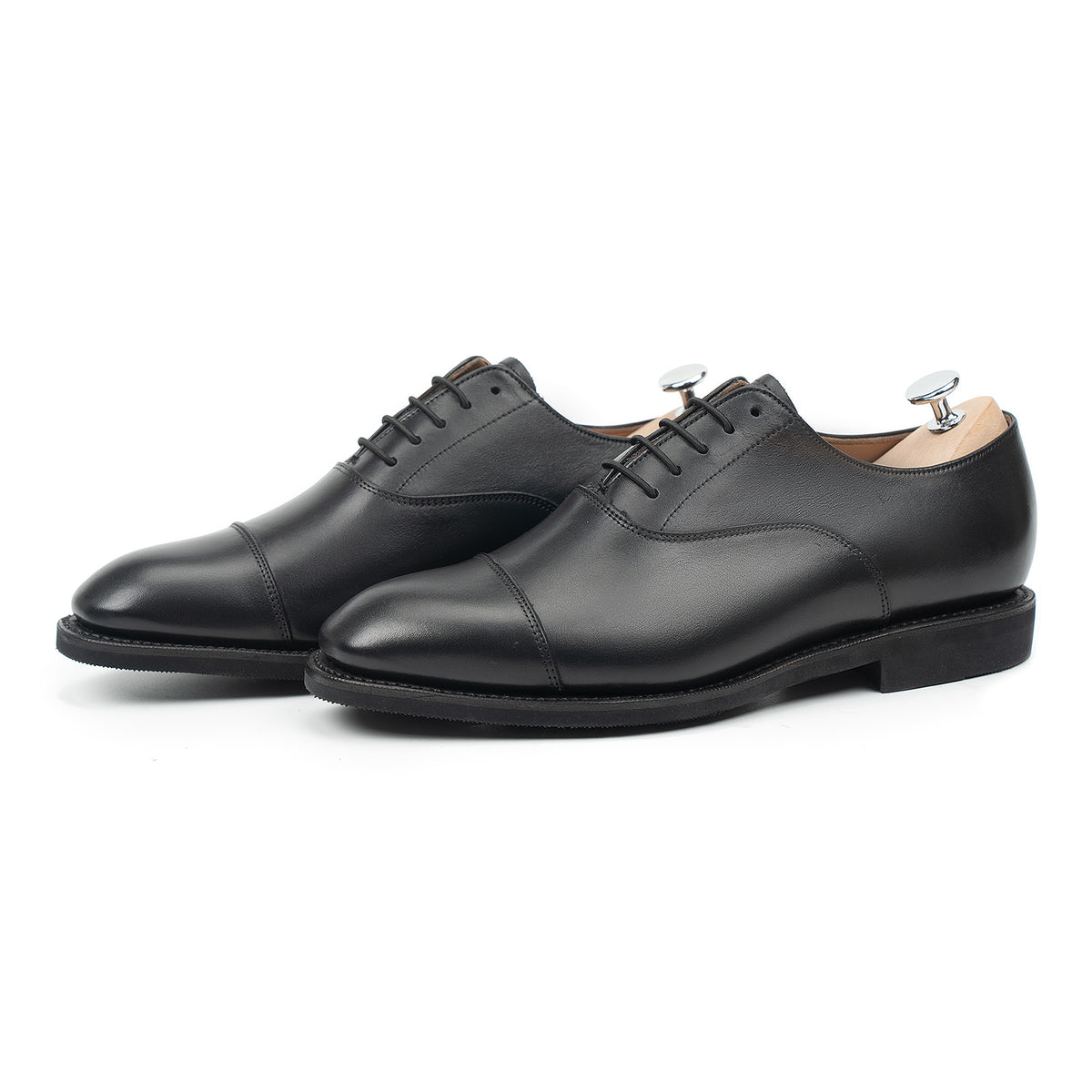 Meermin black silkcalf cap-toe Oxford pair, three-quarter front view with shoe trees inserted, on diamond latex rubber soles