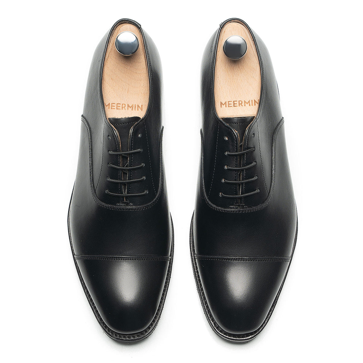 Meermin black silkcalf cap-toe Oxfords, top-down view on shoe trees, showing lacing and toe cap detail on both shoes