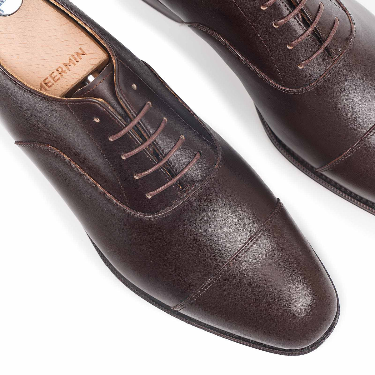 Meermin espresso antique calf cap-toe Oxfords, close-up top view on shoe trees showing lacing and toe cap stitching