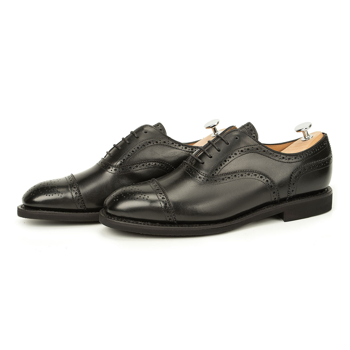 Meermin black boxcalf full brogue Oxford pair, three-quarter side view with shoe trees inserted, showcasing cap-toe perforation detail