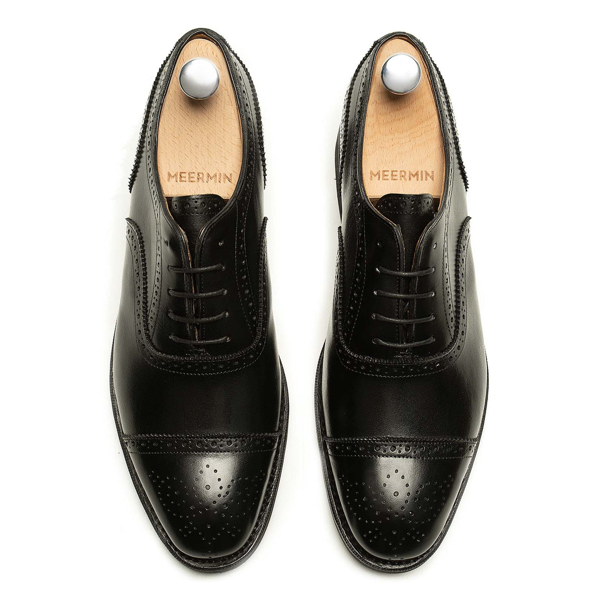Meermin black boxcalf full brogue Oxfords, top-down view on shoe trees, showing cap-toe perforations and lace detailing on both shoes