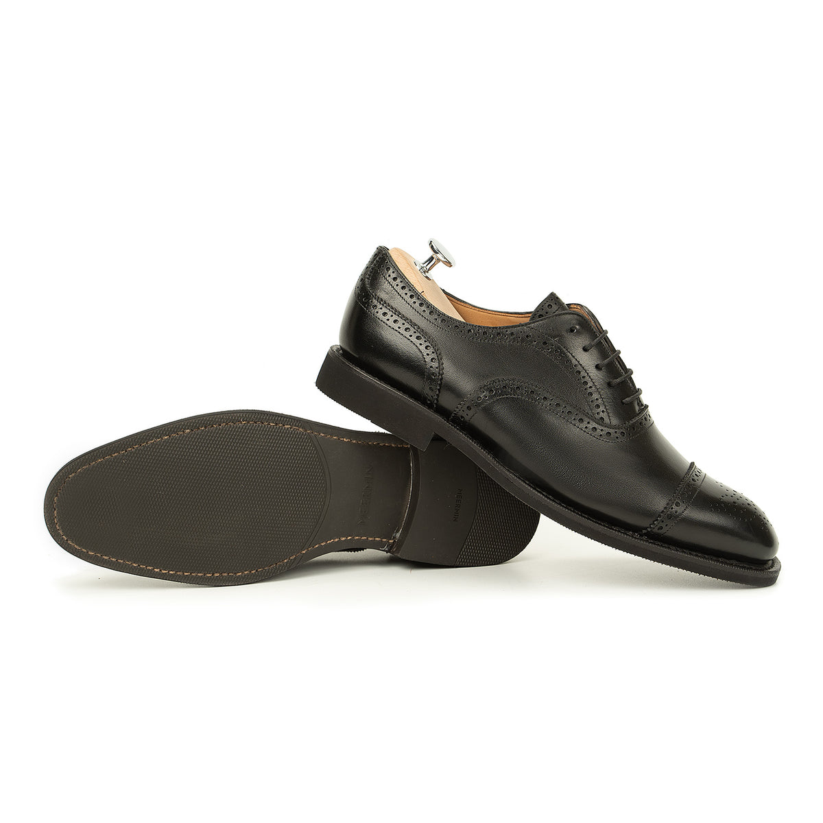 Meermin black boxcalf full brogue Oxford pair, one shoe on shoe tree, the other resting upside down showing diamond latex rubber sole