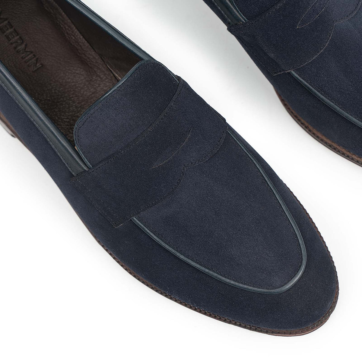 Close-up top view of Meermin navy suede penny loafers, highlighting the piping apron detail and unlined leather insole