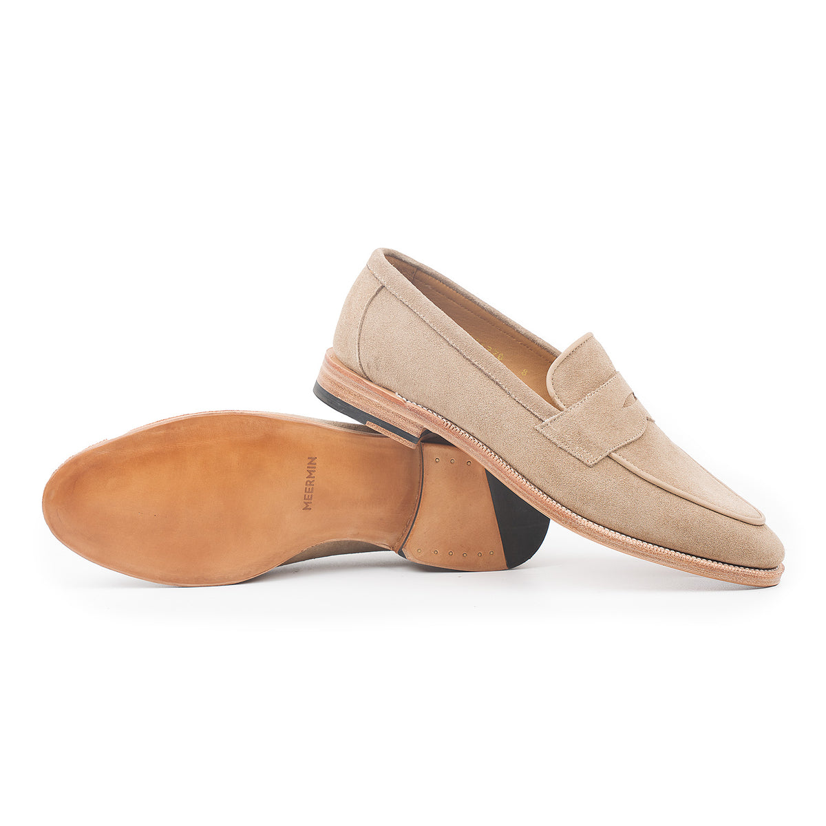 Meermin taupe suede penny loafer pair, one shoe on its side showing flex Goodyear welted leather sole and stacked heel