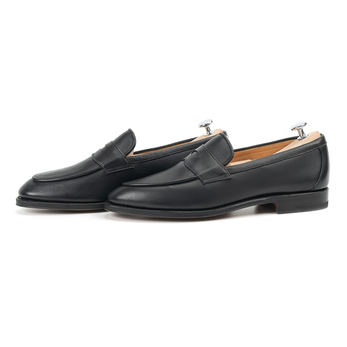 Meermin black softcalf penny loafers, side-by-side profile view with shoe trees inserted, showing apron stitching and low heel