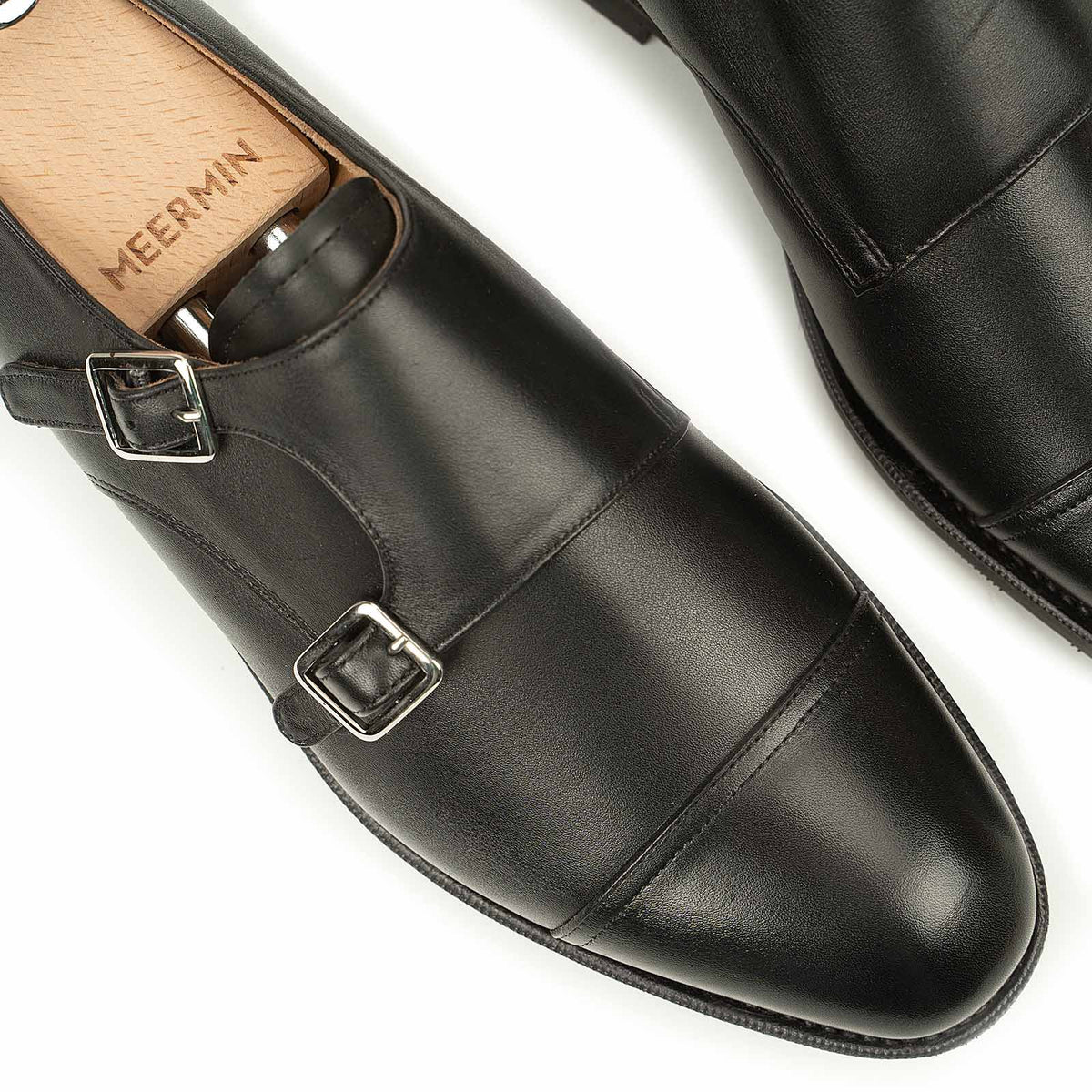 Close-up of Meermin black silkcalf double monkstrap toes, showing buckle straps and cap-toe stitching with wooden shoe trees inserted