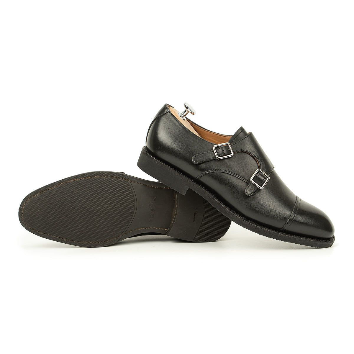 Meermin black silkcalf double monkstrap pair, one shoe upright showing buckles, the other resting on its side revealing the diamond rubber sole