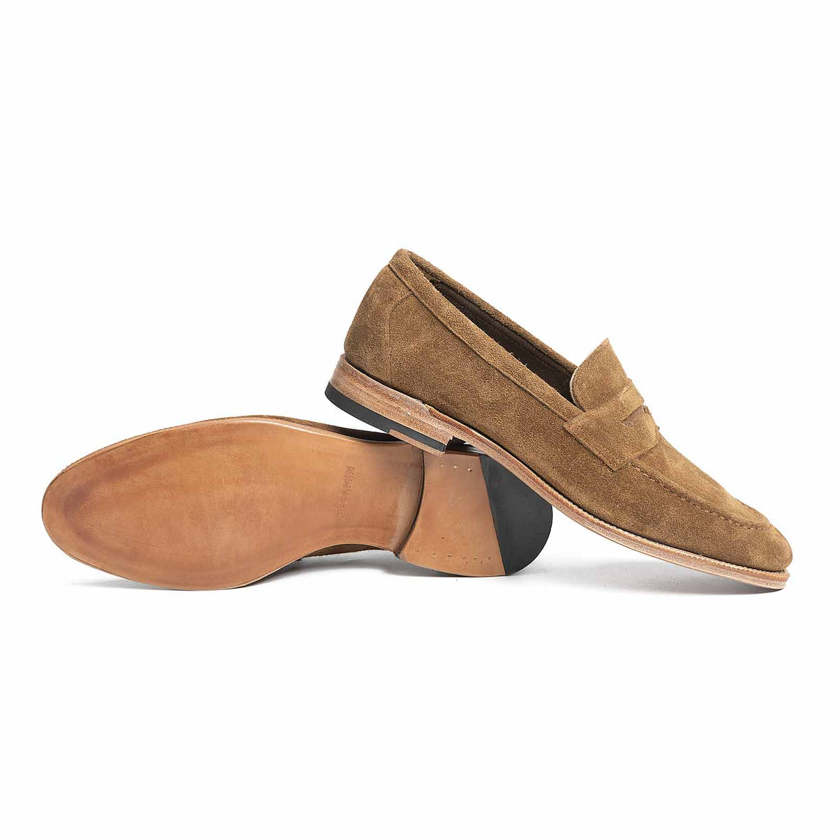 Meermin Atacama suede penny loafers, side view with one shoe resting sole-up against the other, showing leather sole and heel detail