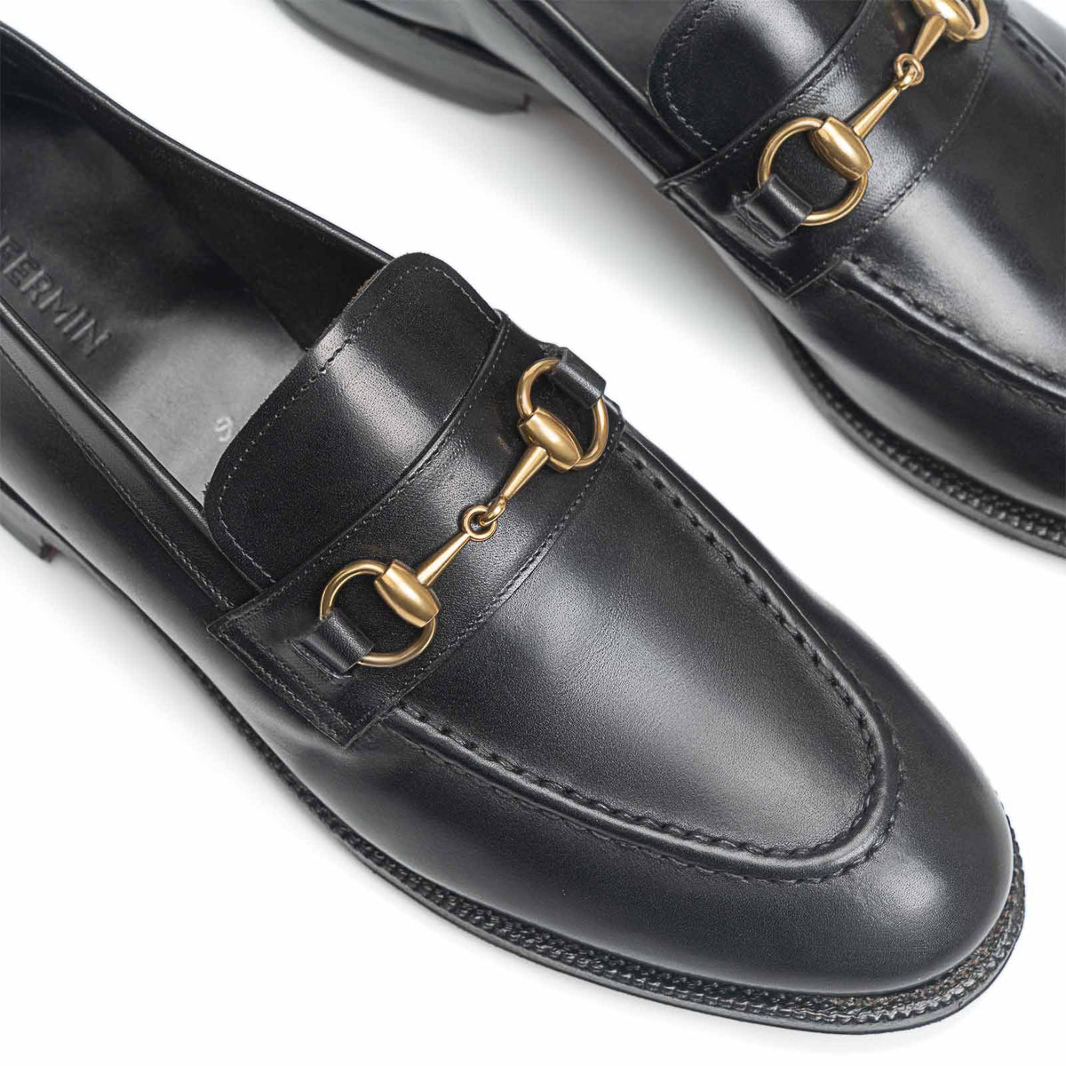 Close-up of Meermin black boxcalf unlined loafers, showing brass horsebit hardware and round toe detail on both shoes