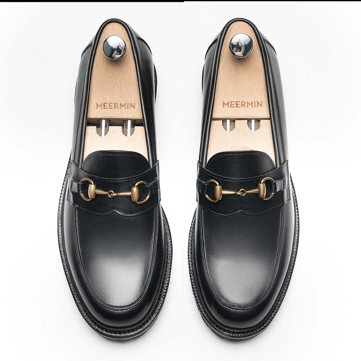 Meermin black boxcalf horsebit loafers, top-down view on shoe trees, showing brass hardware and apron stitching on both shoes